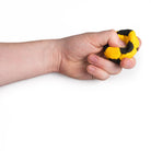 Yellow and black hacky sack in hand being squeezed